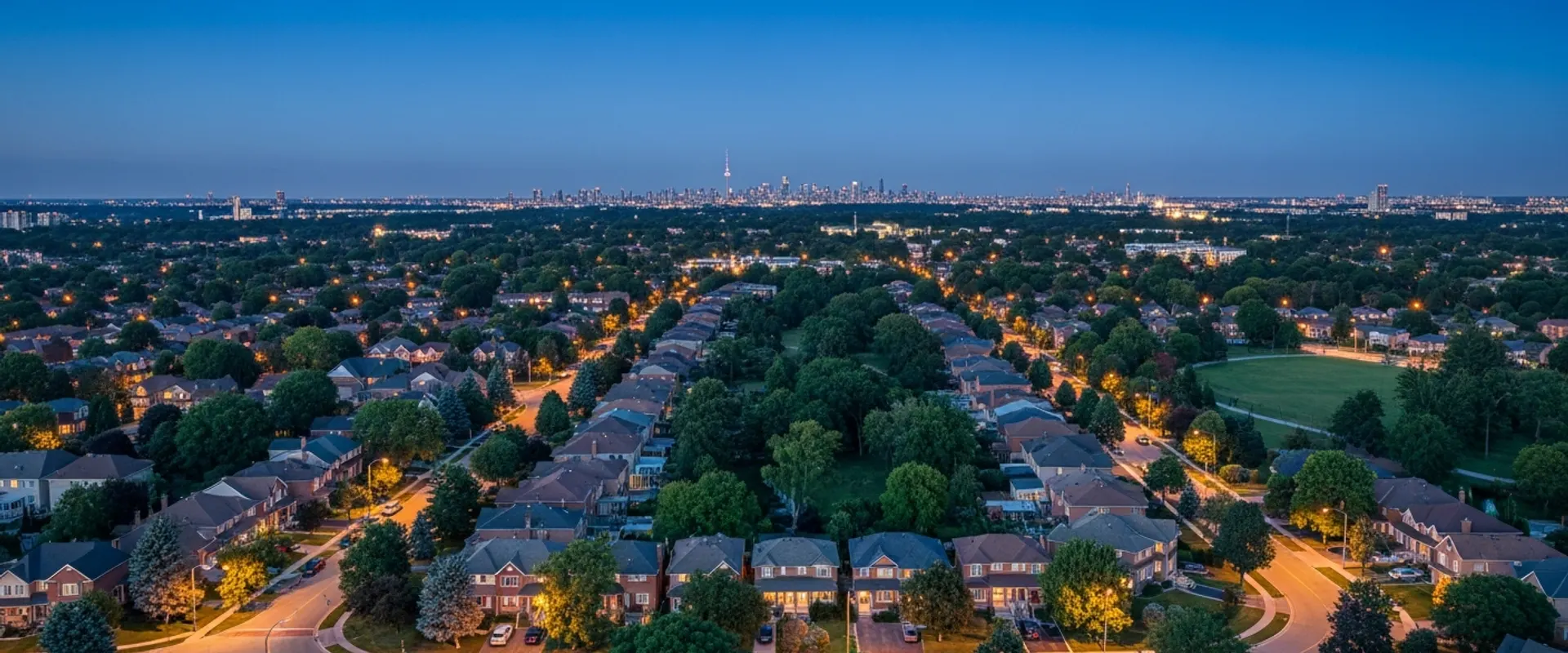High-altitude aerial view of the Greater Toronto Area at dusk — city lights stretching from Lake Ontario northward across the GTA against a deep navy sky